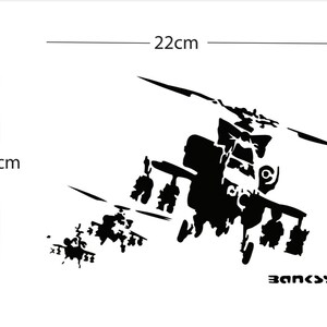 May include: Black and white graphic of a helicopter, 22cm wide and 15cm tall. The design is a silhouette with the word "BANKSY" in the bottom right corner. The image is on a white background.