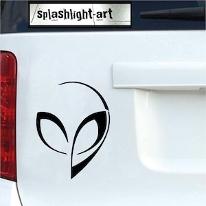 Puede incluir: Pegatina de cabeza de alienígena negra con un diseño minimalista. El texto "splashlight-art" está encima de la cabeza del alienígena. Aplicada sobre una superficie blanca.