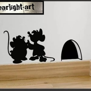Puede incluir: Arte mural de silueta negra que representa dos ratones, un agujero de ratón y el texto "Clearlight-art". La obra de arte está montada en una pared blanca sobre un rodapié de madera.