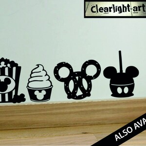 May include: Black silhouette decals of popcorn, soft serve ice cream, a pretzel, and a caramel apple, all in the shape of a famous mouse. The text "clear light art" is visible. The words "ALSO AVAILABLE" are also visible.