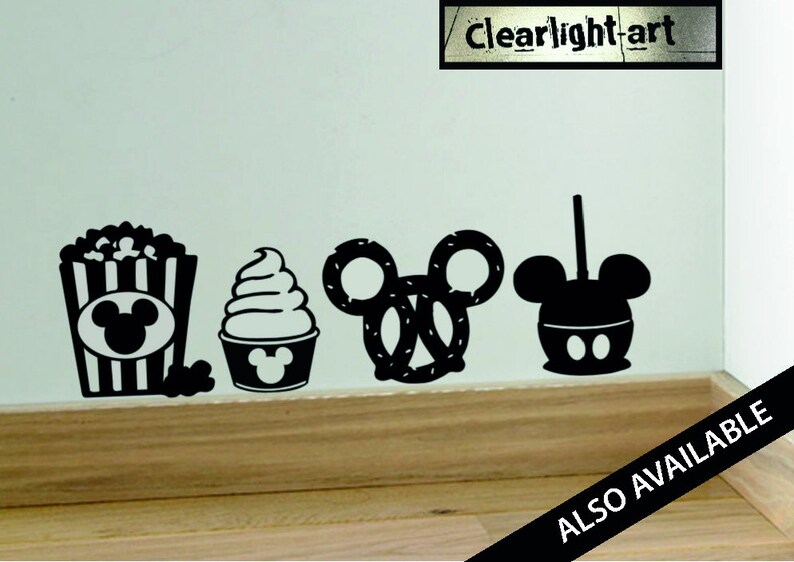 May include: Black silhouette decals of popcorn, soft serve ice cream, a pretzel, and a caramel apple, all in the shape of a famous mouse. The text "clear light art" is visible. The words "ALSO AVAILABLE" are also visible.