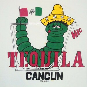 May include: A green worm wearing a yellow sombrero with white flowers and a red and green flag, inside a glass with the word "TEQUILA" in red letters and "CANCUN MEXICO" in black letters below. The worm has a tongue sticking out and a "hic" written in black above it.