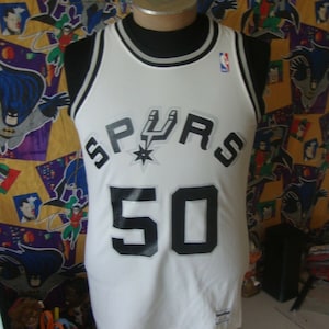 May include: White basketball jersey with black and silver lettering. The jersey says "SPURS" and "50".