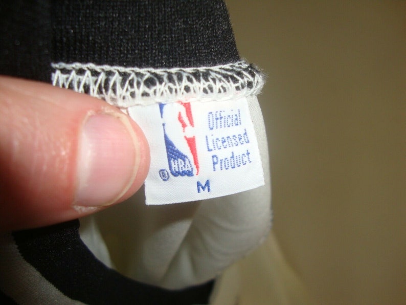 May include: White tag with blue text that reads "Official Licensed Product" and "NBA" logo. The tag also has a size "M" printed on it.