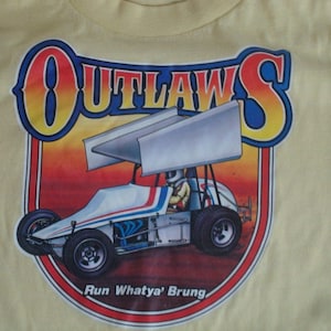 Könnte beinhalten: Ein gelbes T-Shirt mit einem Aufdruck eines Rennwagens mit den Worten "Outlaws" und "Run Whatya' Brung".