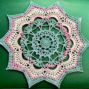 Puede incluir: Un delicado encaje de ganchillo en tonos de rosa, verde y azul, con un diseño de estrella.