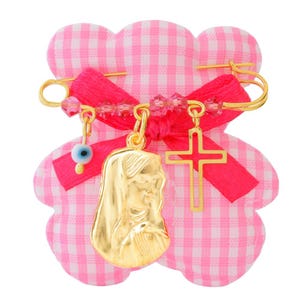 Könnte beinhalten: Eine goldene Babysicherheitsnadel mit einer rosa-weißen Gingham-Schleife, einem blauen Glücksbringer-Auge, einem Kreuz-Anhänger und einem Marien-Anhänger.