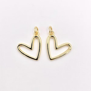 Può includere: Due ciondoli a forma di cuore color oro. Ogni ciondolo ha un anello nella parte superiore per essere appeso. I cuori sono delineati con una finitura liscia e lucida. I ciondoli sono adatti per la creazione di gioielli o l'artigianato.