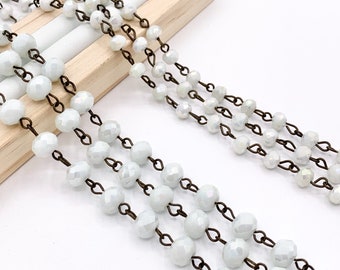 May include: A strand of white faceted glass beads strung on a bronze chain. The beads are round and have a slight iridescent sheen.
