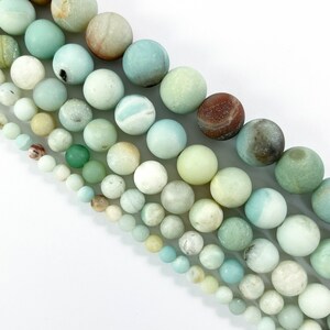 May include: A strand of round, smooth, green, white, and brown gemstone beads. The beads are various sizes and have a natural, polished finish.