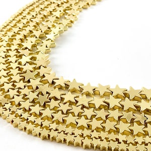May include: A strand of gold-toned star-shaped beads. The beads are arranged in a curved pattern, creating a decorative effect.
