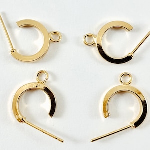 May include: Four gold-toned earring hoops with a post and a jump ring. The hoops are about 1 inch in diameter.