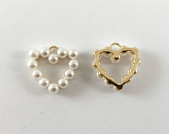 May include: Two gold heart-shaped charms. One charm is made of small white pearls, the other is a hollow gold heart.
