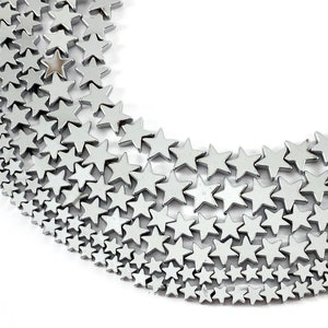 May include: A strand of silver star-shaped beads, arranged in a crescent shape on a white background.
