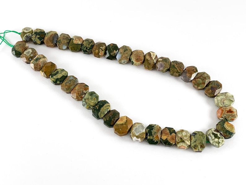 May include: A strand of green, brown, and white gemstone beads. The beads are faceted and have a unique, speckled pattern.