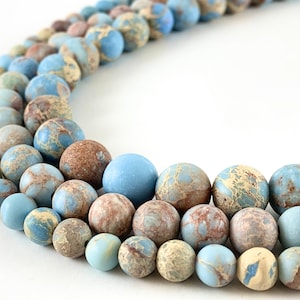May include: A strand of blue and brown marbled round beads. The beads are smooth and have a speckled pattern.