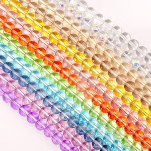 May include: Rows of colorful, round beads in a rainbow of hues. The beads are transparent, with a slight sheen, and arranged diagonally across the frame. Colors include purple, blue, green, yellow, orange, and clear.