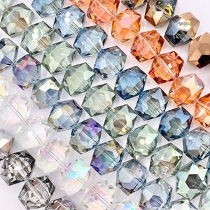 May include: Rows of faceted beads in various colors, including clear, gray, blue, green, orange, and iridescent. The beads are arranged diagonally, showcasing their geometric shapes and reflective surfaces. Ideal for jewelry making.