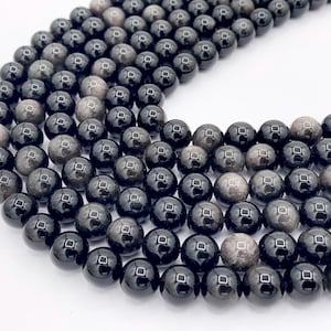 May include: A strand of black gemstone beads with a shimmery, iridescent finish. The beads are round and smooth, and they are strung on a clear thread.