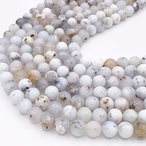 May include: A strand of white and brown speckled round beads. The beads are made of natural stone and have a smooth, polished finish.