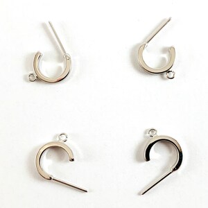 May include: Four silver-toned metal jewelry clasps with a loop on one end and a straight pin on the other end. The clasps are designed to be used for attaching jewelry pieces together.