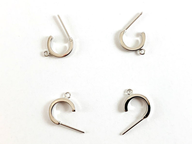 May include: Four silver-toned metal jewelry clasps with a loop on one end and a straight pin on the other end. The clasps are designed to be used for attaching jewelry pieces together.