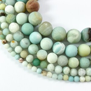 May include: A collection of smooth, round, green and white amazonite beads of various sizes. The beads are arranged in a semi-circle, with the largest beads at the top and the smallest beads at the bottom.