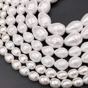 May include: A strand of white baroque pearls, with a variety of sizes and shapes. The pearls are strung on a clear thread and are ready to be used for jewelry making.