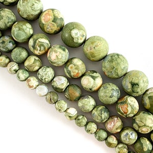 May include: A strand of green, brown and white patterned round gemstone beads. The beads are various sizes and are strung together on a white background.
