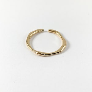 May include: A gold-toned ring with an irregular, organic shape. The ring is made of metal and has a smooth, polished finish.