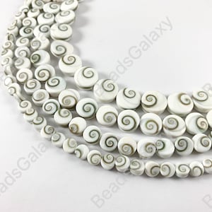 May include: A strand of white and brown shell beads with a spiral pattern. The beads are round and smooth, and they are strung on a white cord.