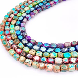 May include: A strand of colorful, square-shaped gemstone beads. The beads are a mix of brown, red, blue, green, and purple with a speckled pattern.