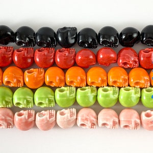 May include: Five rows of skull-shaped beads in black, red, orange, green, and pink. The beads are arranged in rows, with each row containing 10 beads.