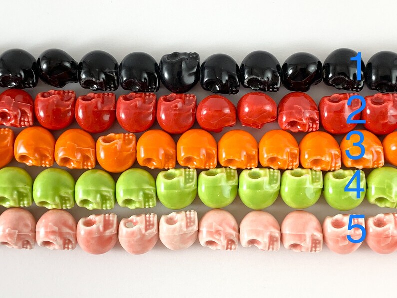 May include: Five rows of skull-shaped beads in black, red, orange, green, and pink. The beads are arranged in rows, with each row containing 10 beads.
