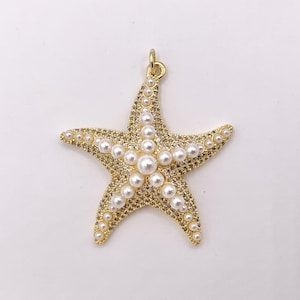 May include: Gold-toned starfish pendant with a loop at the top. The starfish is encrusted with small, clear crystals and adorned with white, round pearls. The pendant is a nautical-themed jewelry piece.