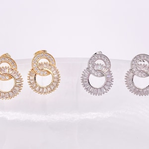 May include: A pair of earrings with two interlocking circles, one gold and one silver, each adorned with clear cubic zirconia stones.