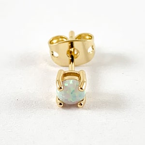 May include: A gold earring with a white opal gemstone.