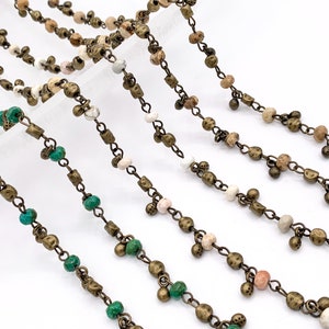 May include: A variety of beaded chains with different colored beads, including green, white, and brown. The chains are made of metal and have a rustic, antique look.