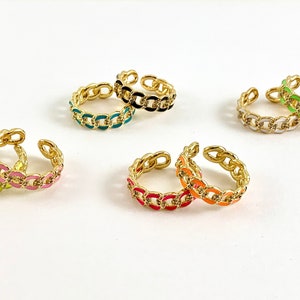 May include: Set of six colorful chain link rings. The rings are made of gold metal and have a variety of enamel colors, including green, pink, blue, black, white, and orange.