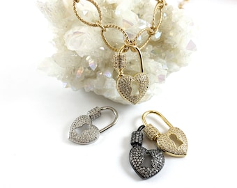 May include: Three heart-shaped lock charms with a keyhole design. The charms are made of gold, silver, and black metal and are adorned with sparkling rhinestones.