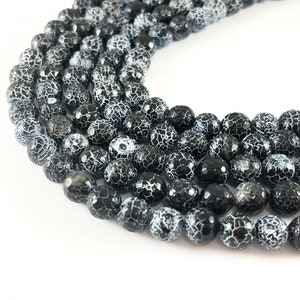 May include: A strand of black and white agate beads. The beads are round and have a crackled surface.