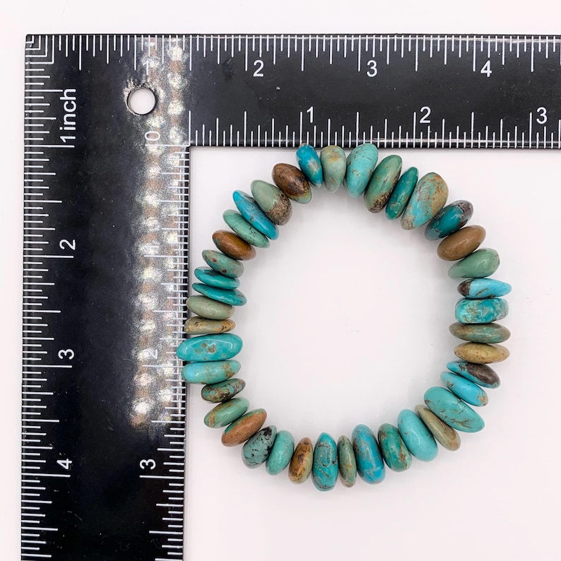 May include: A turquoise bracelet featuring a mix of blue, green, and brown stones. The bracelet is approximately 5 cm in diameter. The oval-shaped stones are strung together in a circular design.