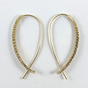 May include: A pair of gold hoop earrings with a delicate, curved design. The hoops are adorned with small, clear crystals that create a sparkling effect.