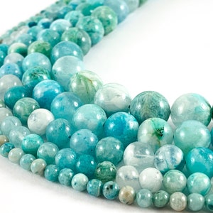 May include: A strand of turquoise and green gemstone beads. The beads are round and have a smooth, polished finish. The beads are arranged in a graduated size, with the largest beads at the top of the strand and the smallest beads at the bottom.
