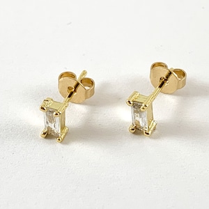 May include: A pair of gold earrings with a rectangular clear stone in the center of each earring.