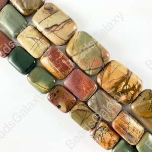 May include: A strand of rectangular, multi-colored, polished gemstone beads. The beads are a mix of brown, green, and red with white and black markings. The beads are approximately 1 inch long and 1/2 inch wide.