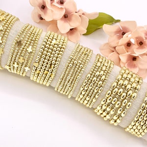May include: A set of gold beaded bracelets with different styles, including some with cross and heart charms.