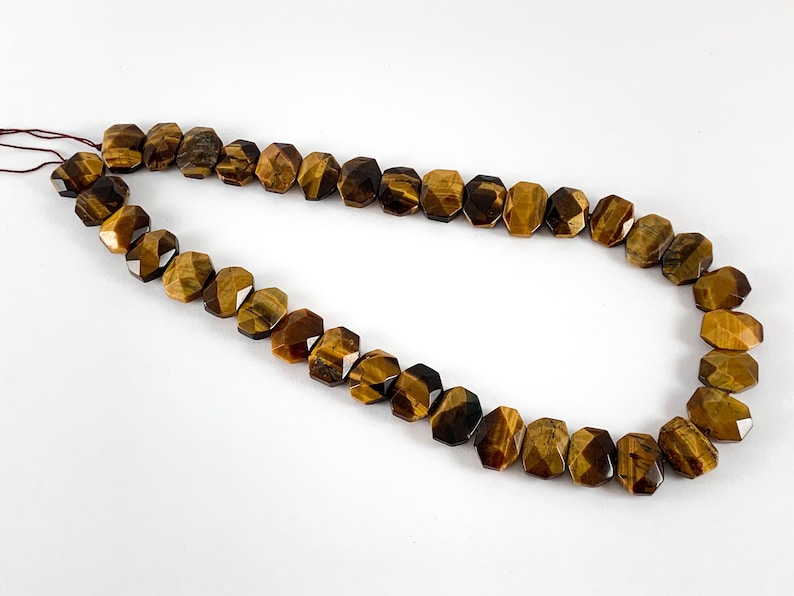 May include: A strand of brown and gold tiger's eye beads. The beads are faceted and have a geometric shape.