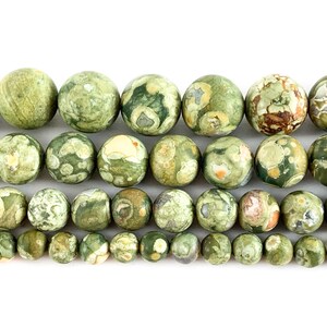 May include: A strand of green, brown and white jasper beads. The beads are round and have a speckled pattern.
