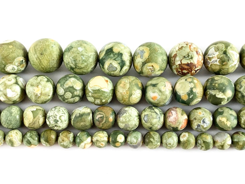 May include: A strand of green, brown and white jasper beads. The beads are round and have a speckled pattern.